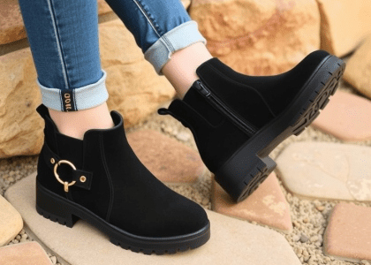 Young woman wearing tan stone shoe boot sandals with jeans details, stylish black booties featuring a lug sole, made from suede material, perfect for work and fashionable outings.